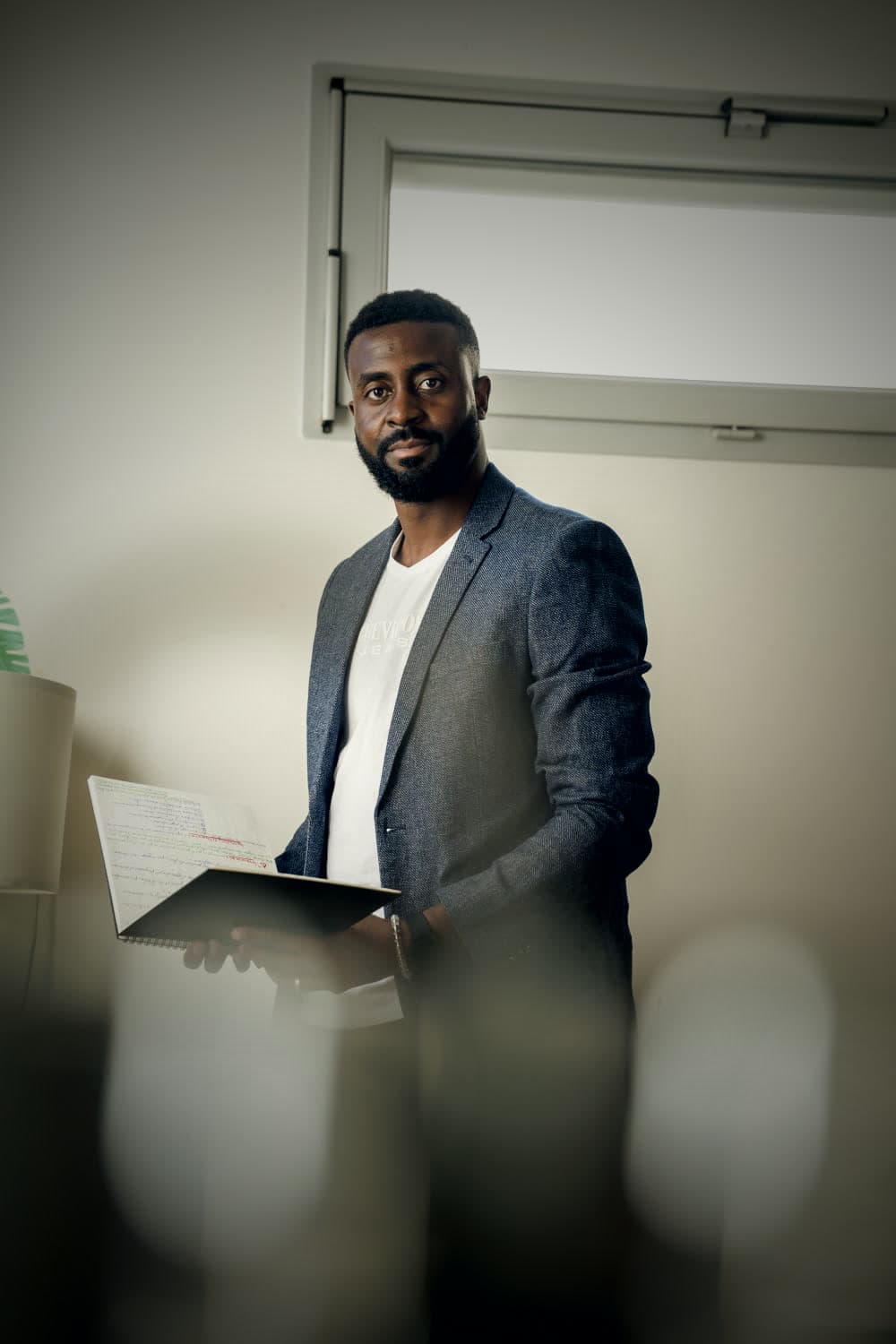 Portrait de Léandry Petnga en veste grise, tenant un carnet